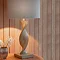 close up on lamp with wooden twisted base and linen shade, on an entryway table emitting a warm glow
