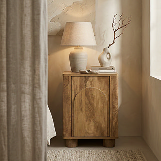image of bedside table in mango wood effect with gentle arch design on the front, in bedroom