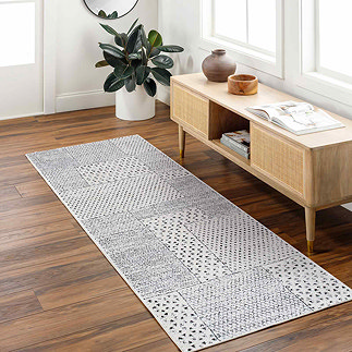 image of geometric black and ivory runner on light wood flooring next to a console table