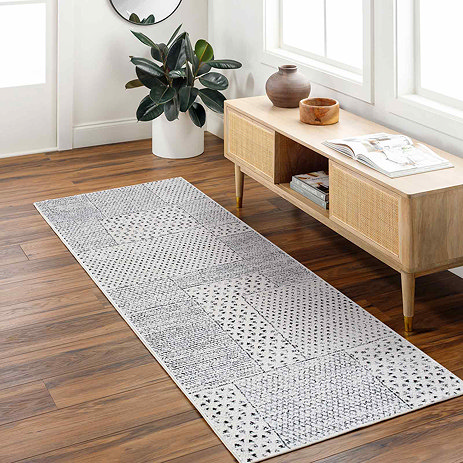 image of geometric black and ivory runner on light wood flooring next to a console table