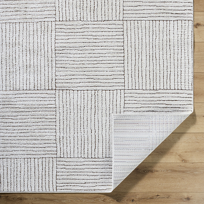 close up image of ivory and brown striped rug with corner folded up slightly to reveal material underneath
