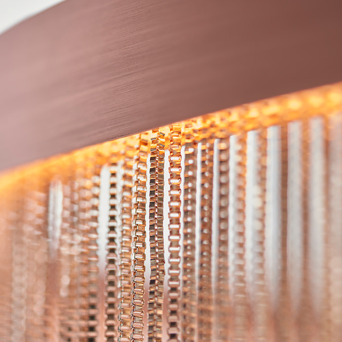 super close up image on copper-effect chains of ceiling light, attached to band of LED light