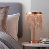 image of brushed copper fringe tasselled table lamp on a bedside table