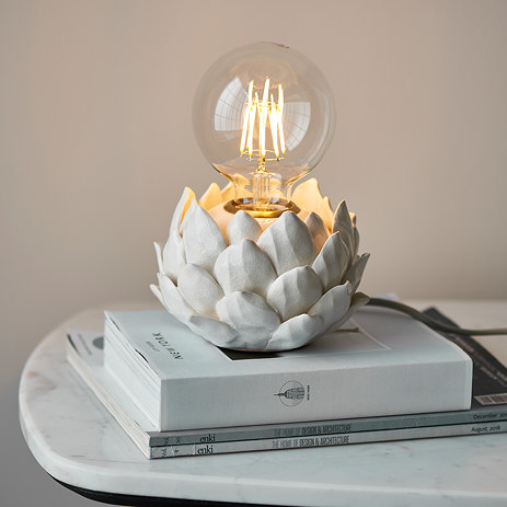 image of round lamp base with artichoke texture in oatmeal colour, on top of a pile of white books