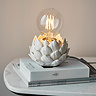 image of round lamp base with artichoke texture in oatmeal colour, on top of a pile of white books