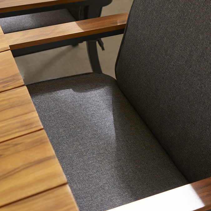 close up image on grey fabric of dining chairs pushed under teak dining table