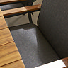 close up image on grey fabric of dining chairs pushed under teak dining table