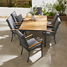 image taken from slightly above of wooden slatted tabletop of rectangular garden dining table with six grey chairs tucked around it, featuring matching teak arms