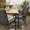 close up image taken from midlevel of teak topped slatted black dining table and matching grey chairs with teak arms