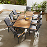 image taken o a patio from above of teak finish slatted outdoor dining table, with eight matching grey chairs with teak arms tucked around it