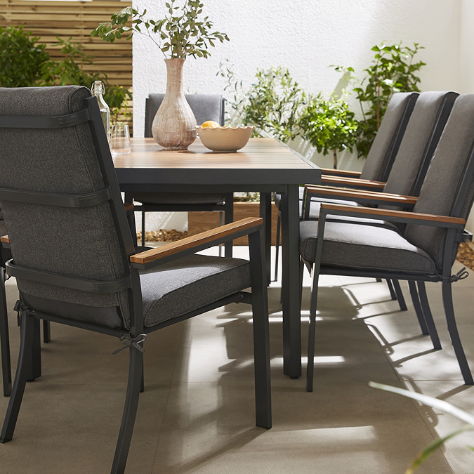 close up image taken at midlevel of grey chairs with teak arms, around rectangular teak coated slatted table
