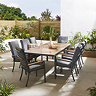 image of slatted teak finish outdoor dining table, with eight black dining chairs tucked underneath