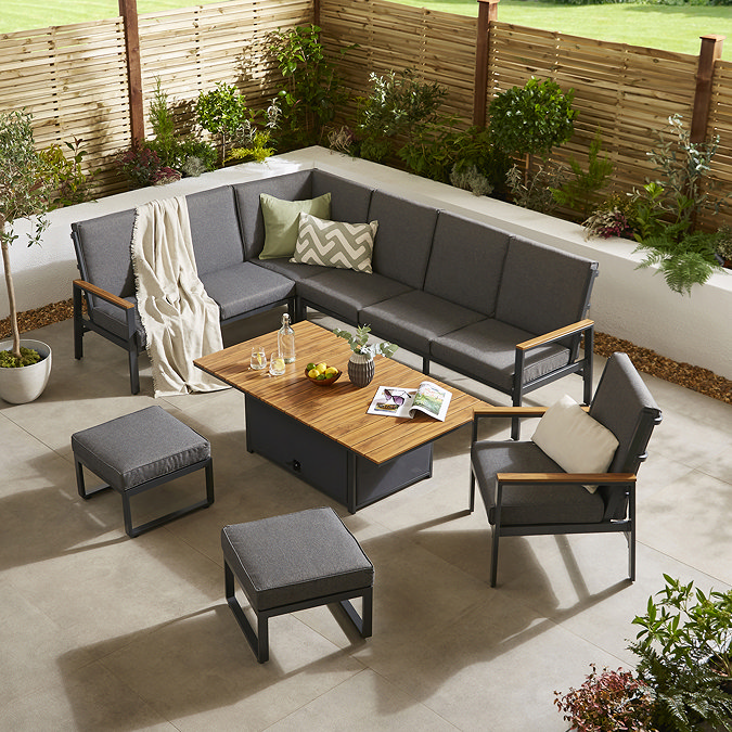 image taken from slightly above of grey corner lounge set with teak arms, matching chair and two stools, around a rectangular coffee table with lifting slatted tabletop