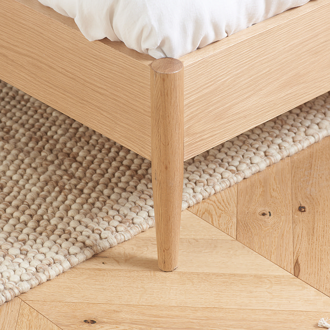 close up on feet of oak bed on wooden floor
