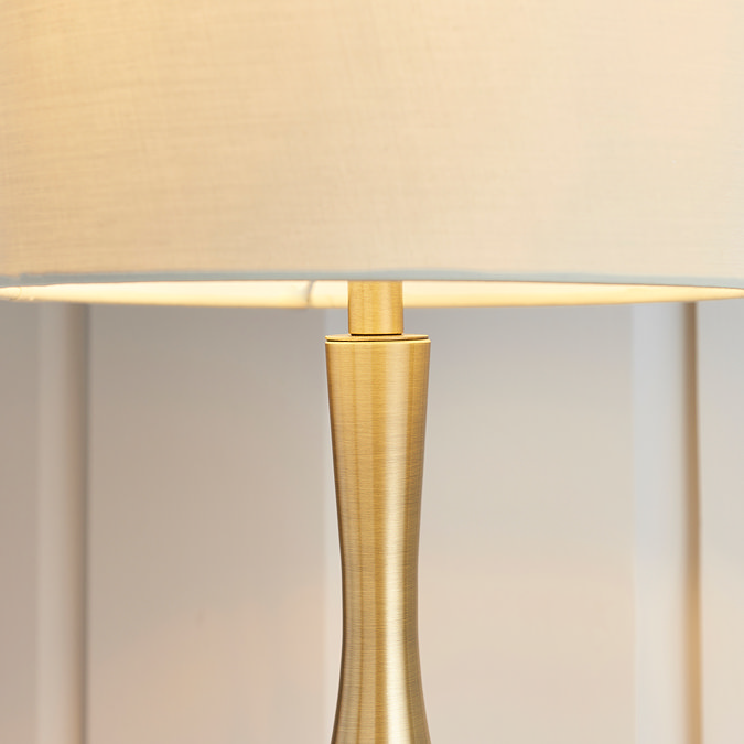 close up on middle of table lamp where linen shade meets brass body