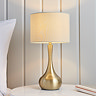 image of brass and taupe table lamp with rounded base on a bedroom side table in front of cream panelled wall