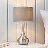 image of modern table lamp with nickel slim body with dark grey fabric shade, on a cream bedside table in front of a cream panelled wall