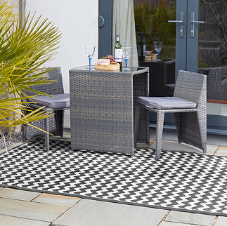 image of onyx patterned outdoor rug under a grey rattan dining set outside