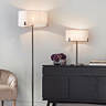 image of bronze floor lamp with linen shade stood next to black sideboard with matching table lamp on top of it