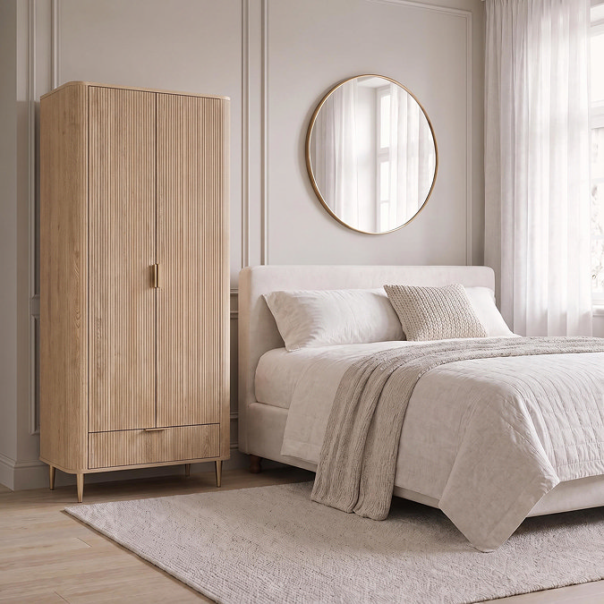 lifestyle image of fluted oak wardrobe next to bed with gold mirror above it