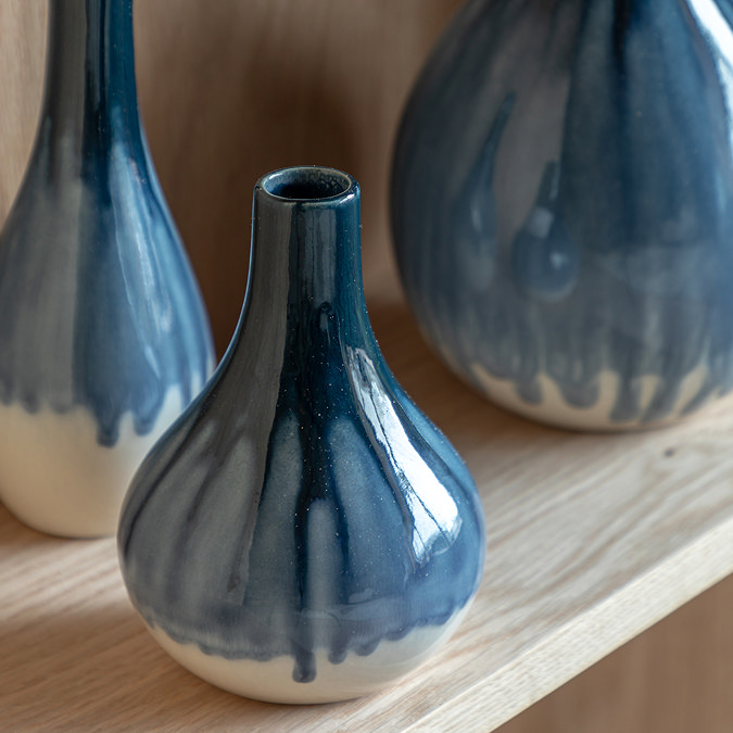 close up image on faded blue and white vase on light wood shelf