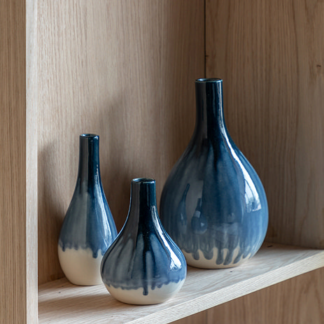 image of three faded blue vases on a light wood shelf