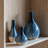 image of three faded blue vases on a light wood shelf