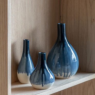 close up image on faded blue and white vase on light wood shelf