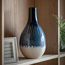 image of faded blue vase with drip effect at the bottom, on a light wood shelf