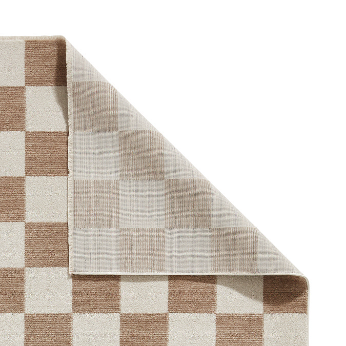 image cut out on white background of beige checkered rug with corner folded over to show floor-facing material