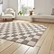 angled image of grey checkered rug on light wooden flooring