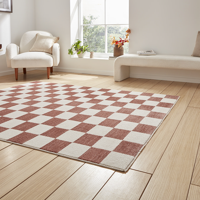 angled image of checkerboard rug in plum and cream on light wooden floor