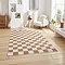 image of walnut brown and cream checkerboard rug on light wooden flooring of modern loft apartment