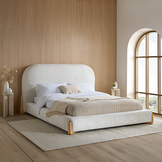 image of white boucle bed with curved headboard and light wood legs on large white jute rug in bedroom