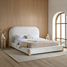 image of white boucle bed with curved headboard and light wood legs on large white jute rug in bedroom