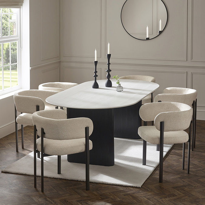 image of oval white marble effect dining room with chenille dining chairs round it, candles on top 