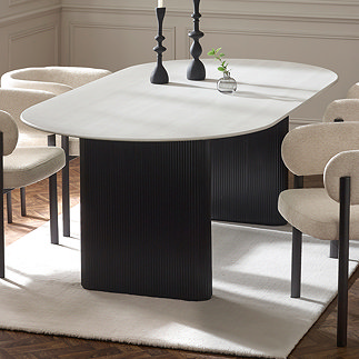 image of oval marble white dining table with black fluted pedestal legs on white rug with cream chenille dining chairs