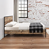 side on image of wood effect and black metal edged bed, on wooden flooring of industrial style bedroom