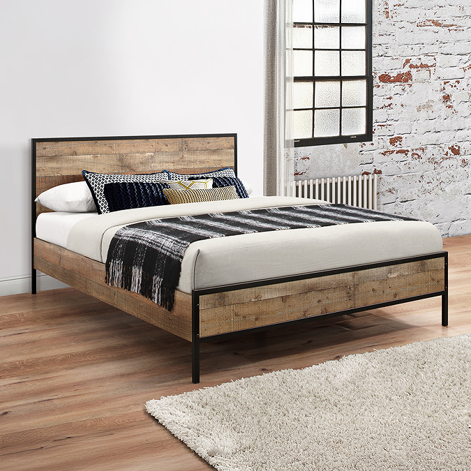 image of wood effect and black metal bed in industrial style bedroom with exposed brick wall