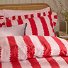 close up image of top of bed covered in red and pink striped duvet, with matching cushions edged in ruffle trim