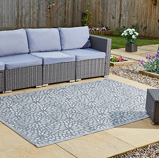 image of slate grey-blue floral patterned rug on patio next to rattan lounge set