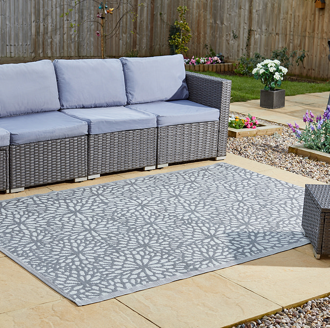 image of slate grey-blue floral patterned rug on patio next to rattan lounge set