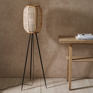 image of boho style floor lamp with linen shade and black legs, in corner of room with wooden flooring