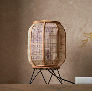 image of natural rounded rectangular table lamp with black metal legs on a side table in front of a warm brown wall
