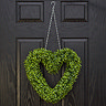 image of a heart-shaped green wreath hanging on a black front door by a chain