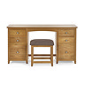 image cut out on white background of solid wood dressing table with six drawers and padded stool pushed underneath