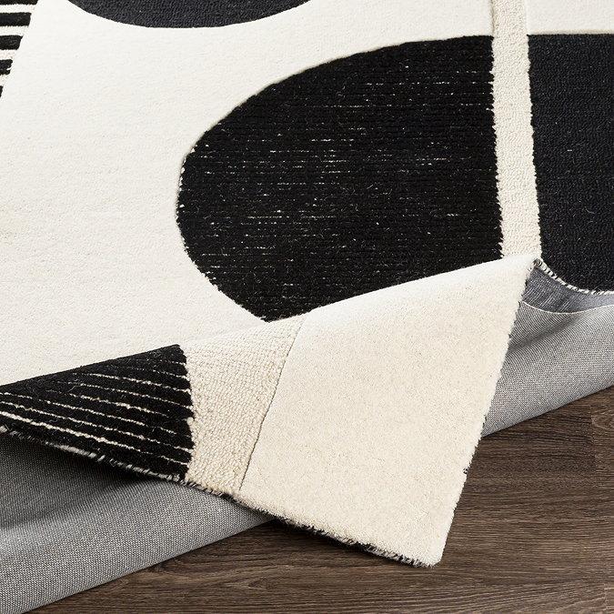 close up image on cream and black geometric rug ruched slightly to show thickness and material underneath