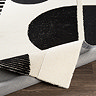 close up image on cream and black geometric rug ruched slightly to show thickness and material underneath