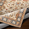 close up image of vintage floral tan coloured rug folded slightly to show its thinness