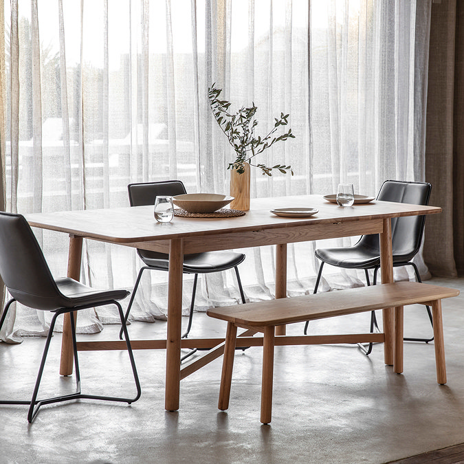 image of extendable oak table in dining room with matching bench and grey chairs